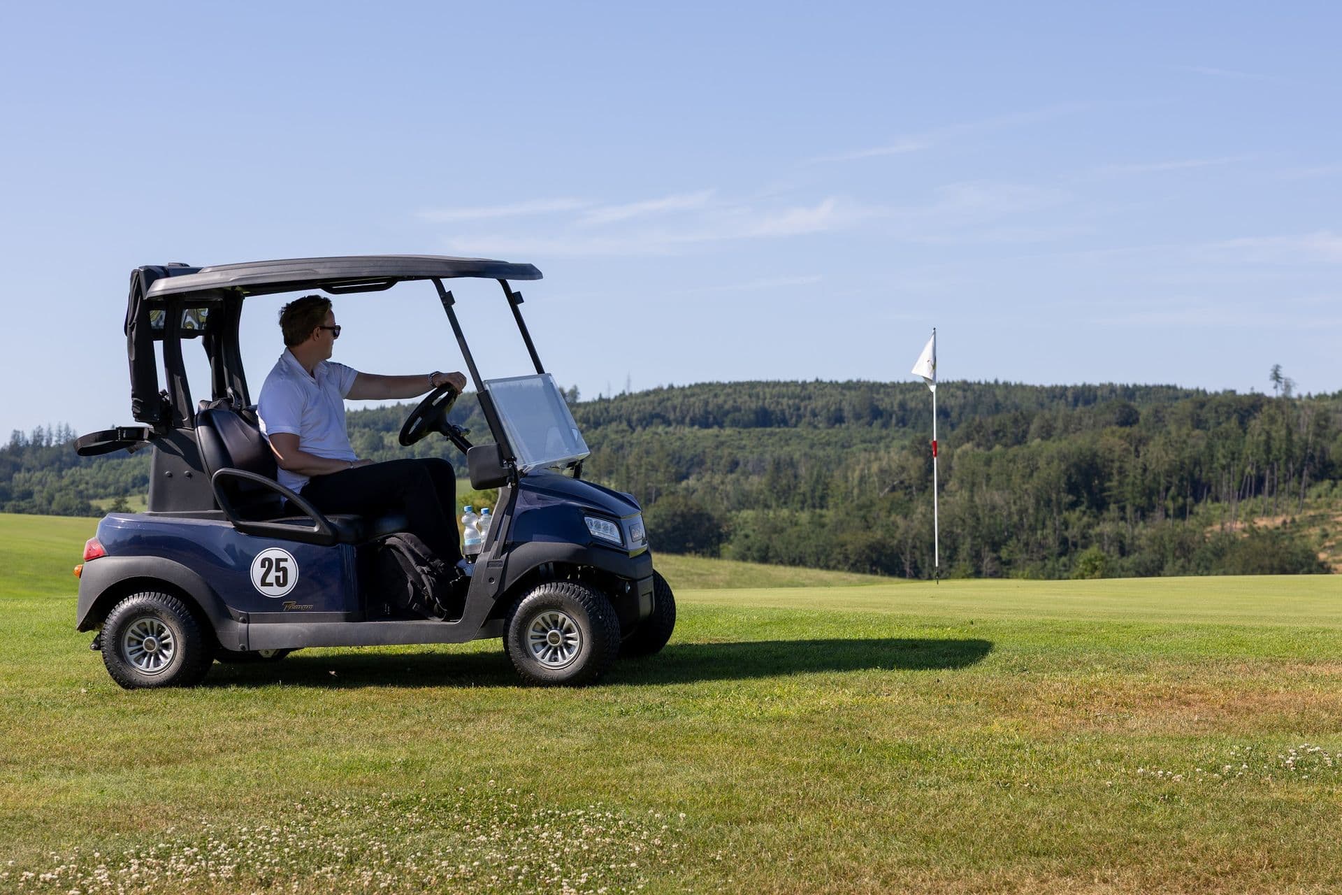 Golfcart auf dem Weg über den Platz, im Hintergrund die weite Landschaft