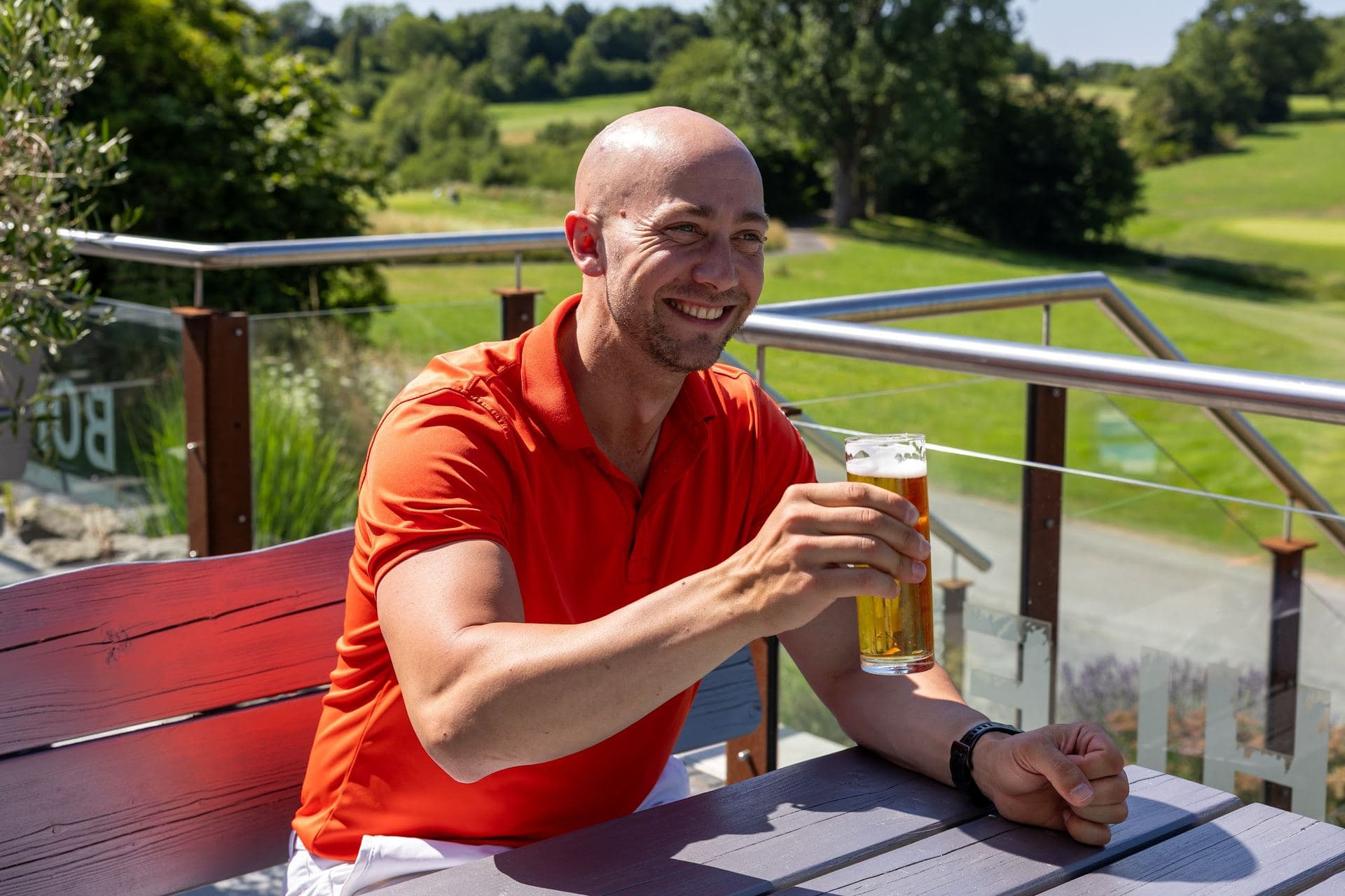 Mitglied mit einem frisch gezapften Bier auf der Terrasse