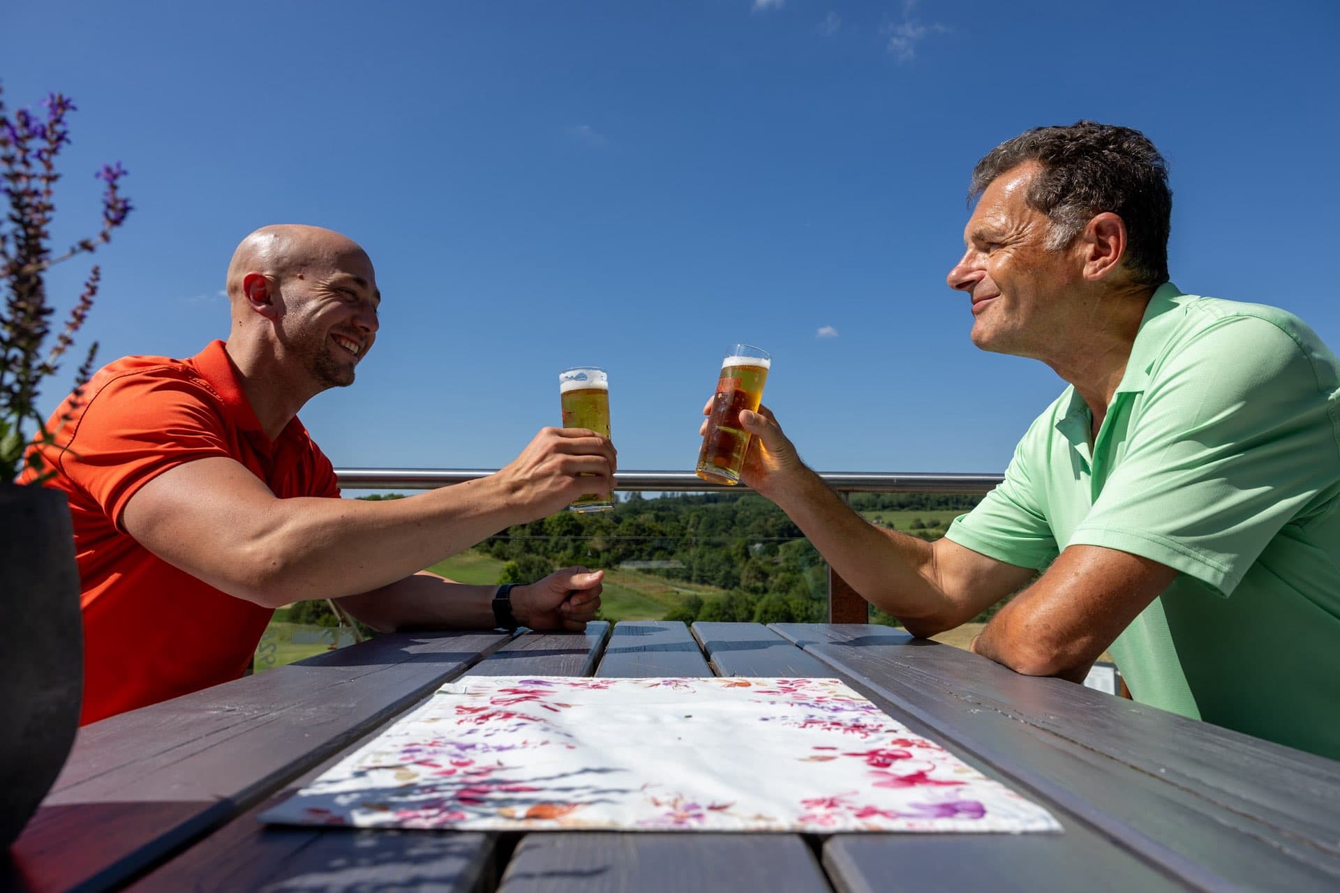 Zwei Spieler stoßen mit Biergläsern auf der Terrasse an