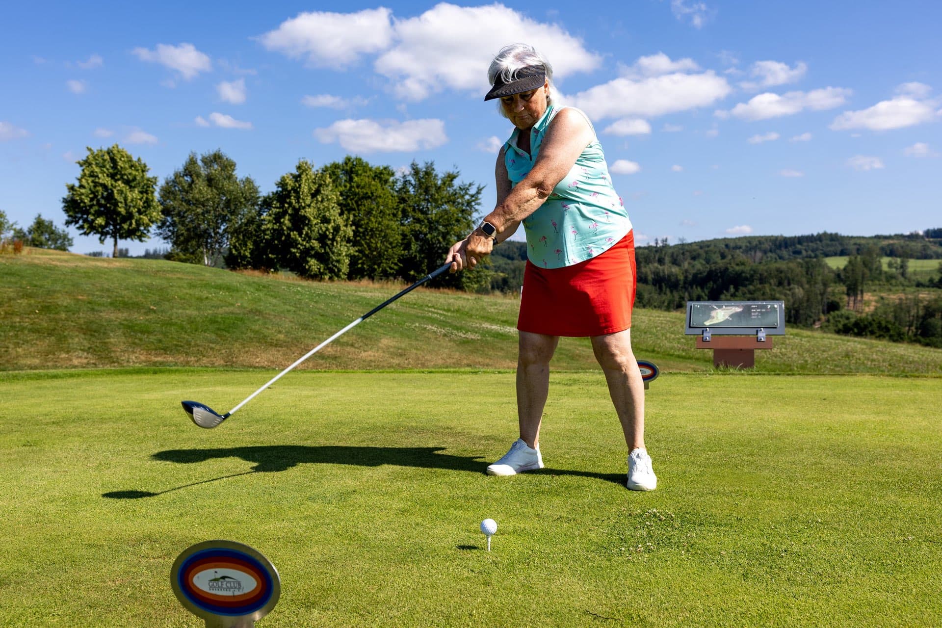 Ältere Spielerin spricht den Ball mit dem Driver am Abschlag an