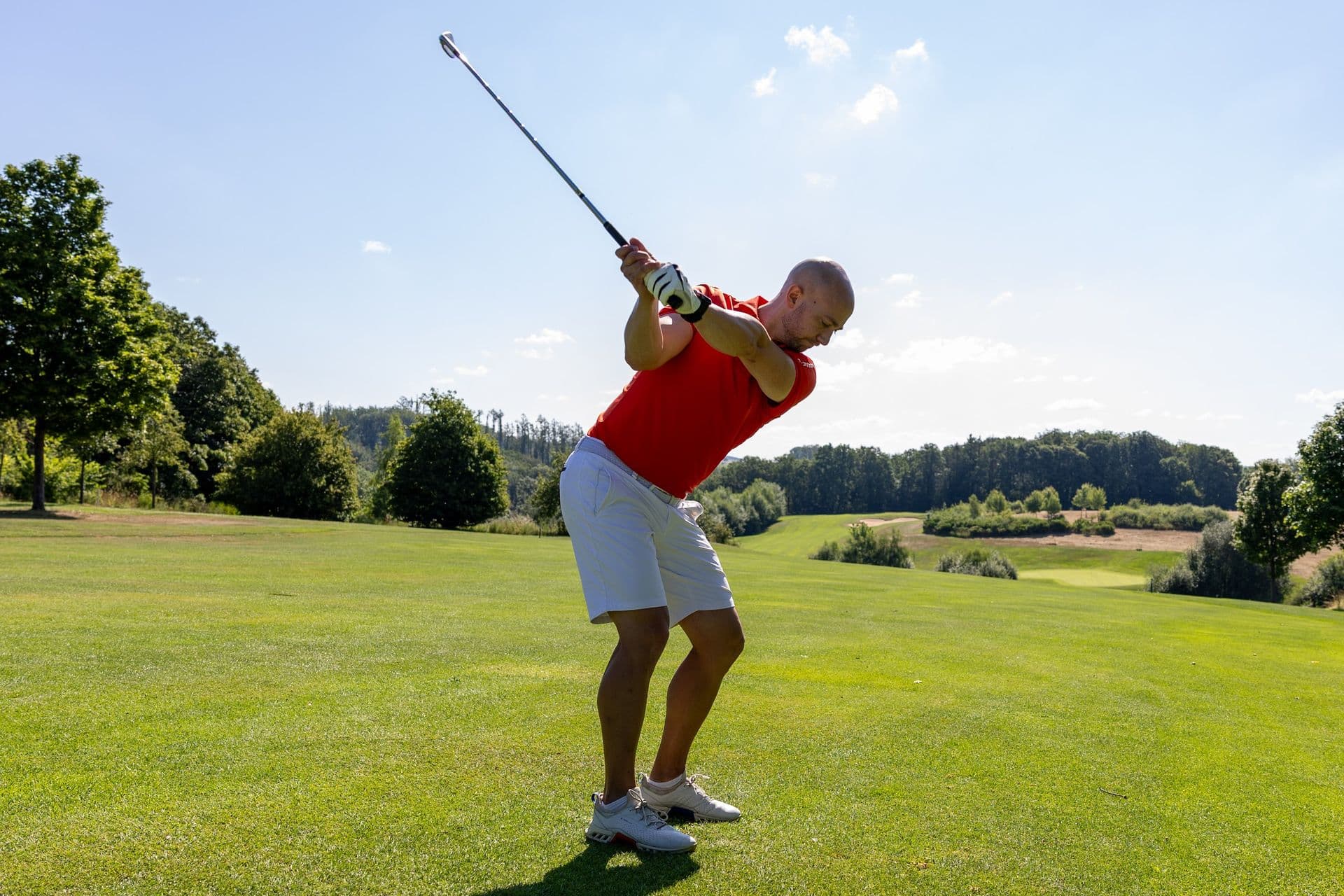Golfer beim Abschlag mit weitem Blick ins Tal