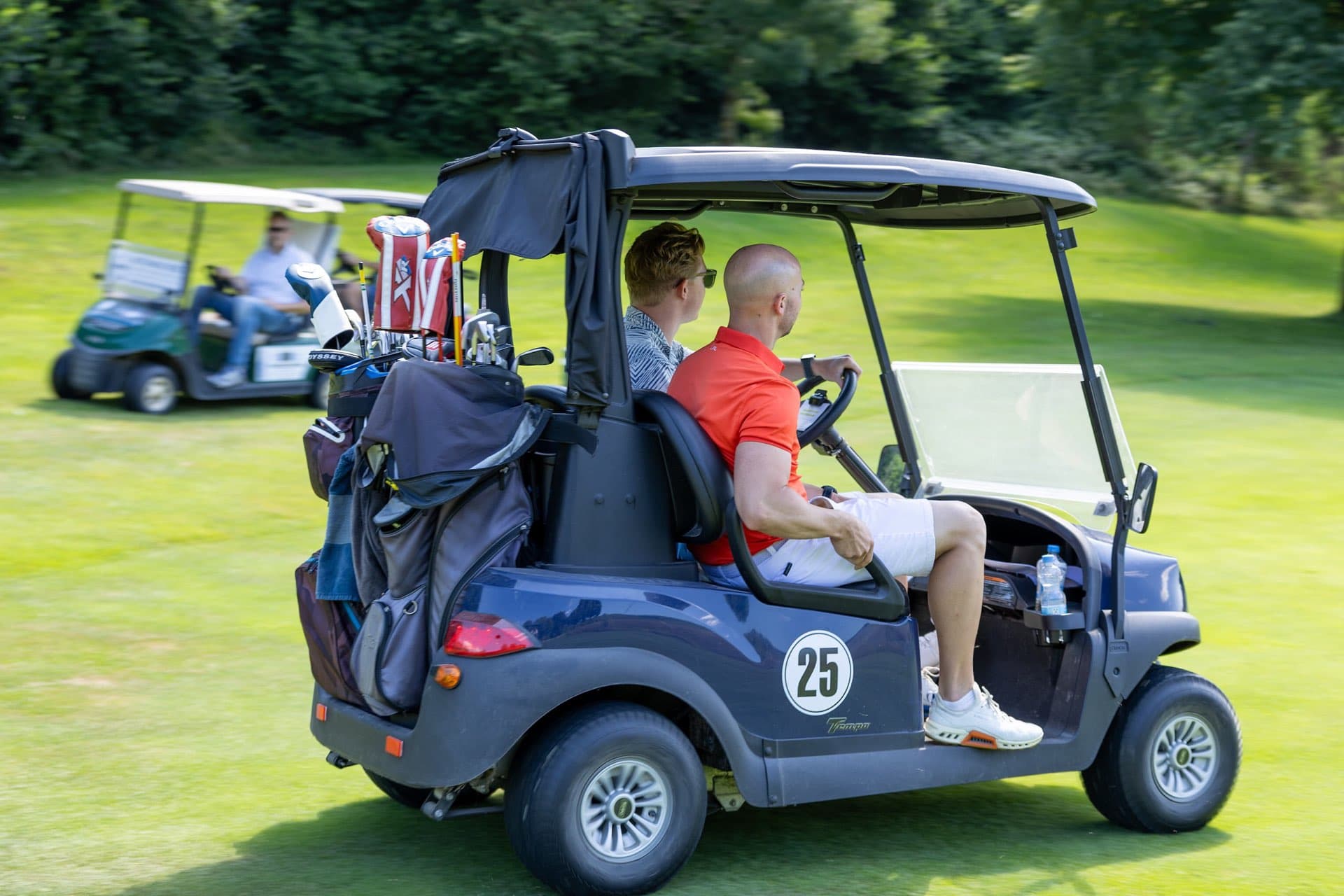 Zwei Spieler in einem Golfcart mit Bags auf dem Fairway
